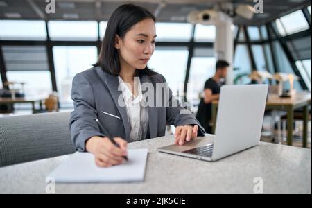 Young Asian business woman office employee using laptop watching webinar. Stock Photo