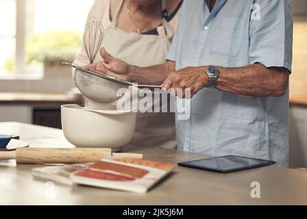 Sometimes all you need is to bake a cake. an unrecognizable couple baking together at home. Stock Photo