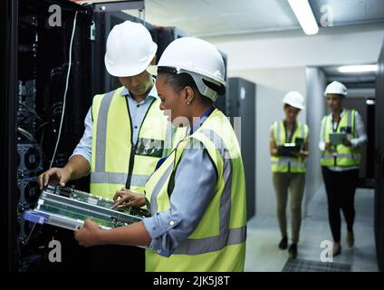 Technology doctors. a group of computer programmers working in a server room. Stock Photo