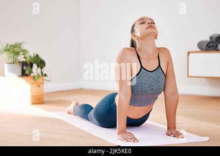 Stretching away all the negativity. a young woman practicing yoga at home. Stock Photo