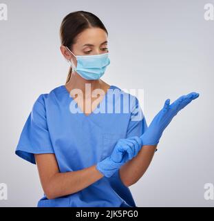 I have to protect myself at all costs. a female nurse putting on her protective gloves. Stock Photo