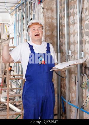 Happy contractor pointing pen up while planning building works, having good idea or smart construction solution Stock Photo