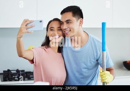 Lets take a photo together. a couple taking a break from cleaning to take a selfie. Stock Photo