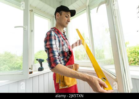 Man measuring window prior to installation of roller shutter outdoors. Stock Photo