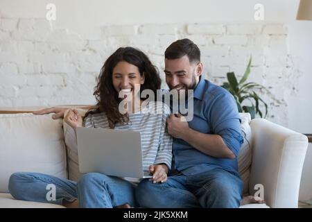 Excited millennial married couple looking at laptop computer screen Stock Photo