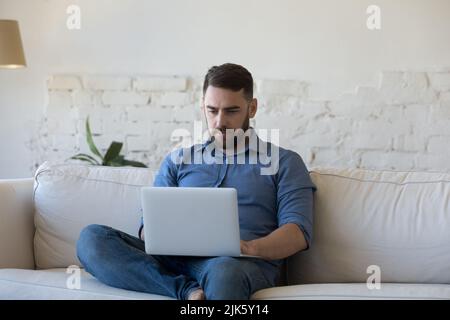 Serious freelance employee man using laptop computer Stock Photo