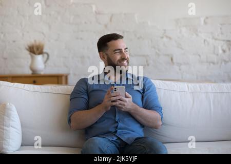 Happy dreamy cellphone user man holding mobile phone Stock Photo