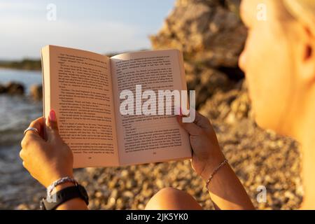 A girl is reading a book on the Adriatic beach, Croatia