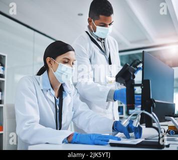 Working hard to get the result we want. two young researchers using a computer in a laboratory. Stock Photo