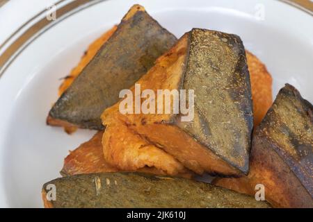 Close up shot of baked pumpkin in a plate with wooden background. Stock Photo