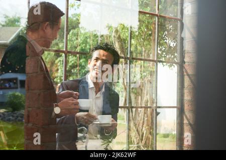 Cheerful business people drinking coffee and discussing plans Stock Photo