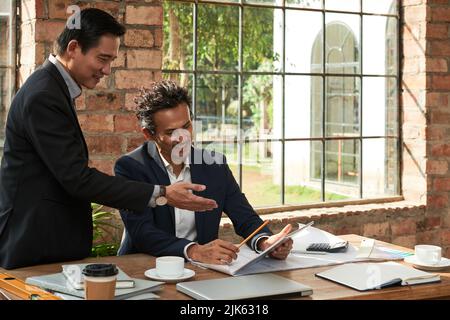Cheerful Asian business people reading something on tablet screen Stock Photo