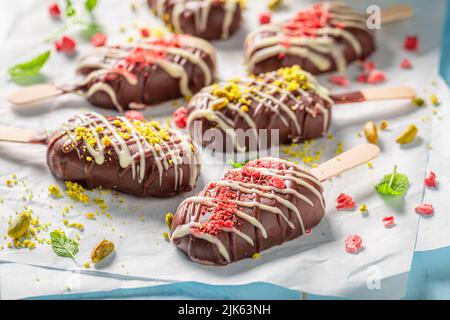 Delicious and homemade popsicles with chocolate topping and pistachios. Popsicles looking like small ice cream. Stock Photo