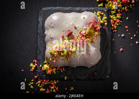 Sweet monoportion with dry strawberries and pistachios on black rock Stock Photo