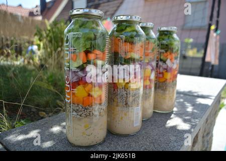 Three glass jars with layering various vegan salads for healthy lunch. The concept of fitness and vegetarian food. Stock Photo