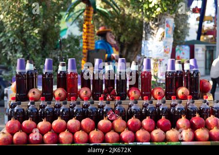 Fresh pomegranates on the market. Pomegranates for juice on the counter of the fruit street market. Freshly squeezed pomegranate juice, bottled in pla Stock Photo