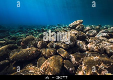 Underwater seascape with stones and blue water with sun rays. Stock Photo
