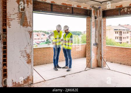 Two adult construction architect men working on digital tablet at building site Stock Photo