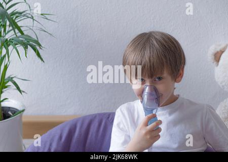 Unwell kid with chamber inhaler for cough treatment . Healthcare and medication. Stock Photo