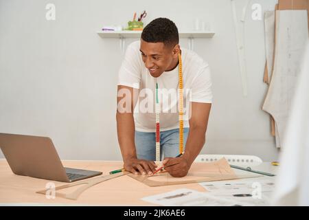 Jolly fashion designer using laptop in atelier Stock Photo
