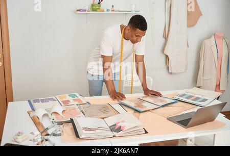 Young tailor working with drawings and laptop Stock Photo