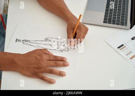 Fashion designer creating clothes on paper before laptop Stock Photo