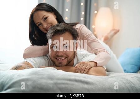 Smiling woman hugging the back of her beloved man Stock Photo