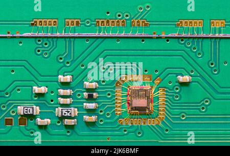 Integrated circuit die wired to green printed board texture with line scan camera. Close-up of chip bonded by gold wires to PCB inside flatbed scanner. Stock Photo