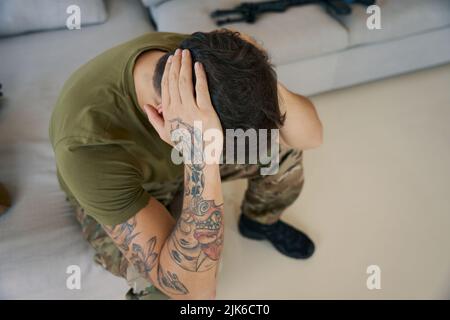 Man of arms experiencing mental problems and holding his head Stock Photo