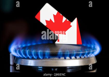 Decreased gas supplies in Canada. A gas stove with a burning flame and an arrow in the colors of the Canada flag pointing down. Concept of crisis in Stock Photo