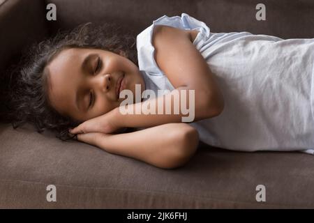 Sweet pretty Indian girl kid resting on comfortable sofa Stock Photo