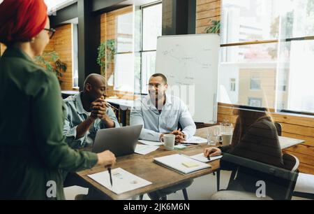 Creative business team sharing ideas during a boardroom meeting. Group of multicultural business professionals having a discussion in an inclusive wor Stock Photo