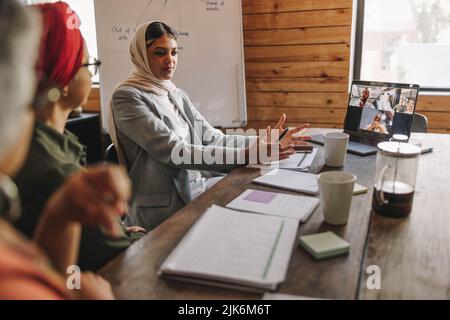Muslim businesswoman leading a discussion during an online meeting in a creative office. Group of multicultural businesswomen having a video conferenc Stock Photo