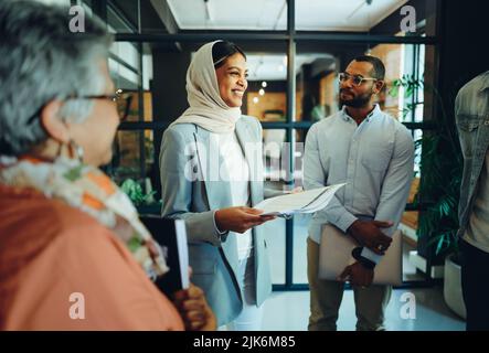 Group of diverse businesspeople holding a staff meeting in a modern office. Team of multicultural entrepreneurs running a successful startup in an inc Stock Photo