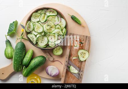 Cucumber salad. Preparation of fresh cucumber salad on white background Stock Photo