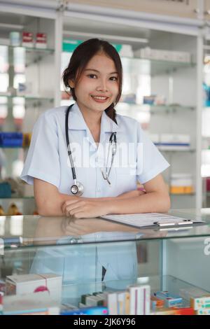Medicine and health concept, Female pharmacist stand with crossed arms in front of medicine shelves. Stock Photo