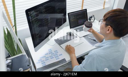 Software development concept, Male programmer checking website programming and drinking coffee. Stock Photo