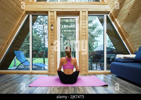 Woman practicing yoga lotus position in forest house Stock Photo