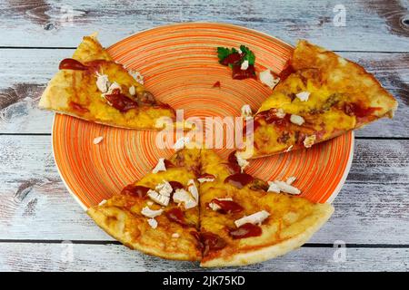 Half-eaten homemade pizza with cheese, chicken meat, olives, ketchup on plate. Tasty unhealthy fast food snack of Mediterranean food. Close-up. Stock Photo