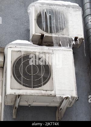 Outdoor inverter compressor unit of split-system air conditioner installed outside the building. Equipment in ice in the winter season. High quality photo Stock Photo