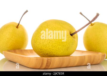 Three organic bright yellow pears on a wooden tray, close-up, isolated on a white background. Stock Photo