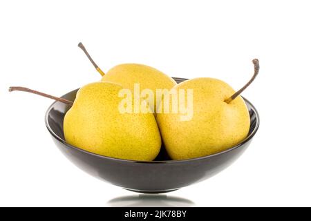 Three organic bright yellow pears on a ceramic plate, close-up, isolated on a white background. Stock Photo