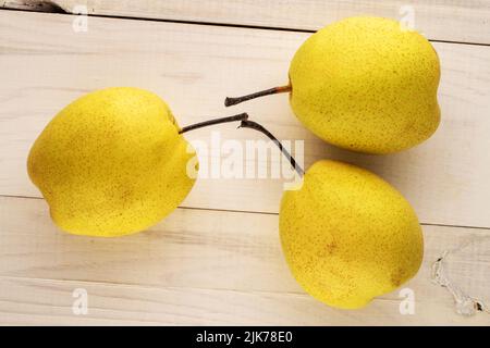 Three sweet bright yellow pears on a wooden table, close-up, top view. Stock Photo