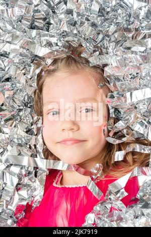 Smiling cheerful face of a girl in a huge pile of confetti made of silver foil, close-up. A girl in sparkling sequins. Happy birthday, Christmas, New Stock Photo