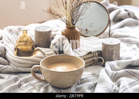 Cozy autumn composition with a cup of coffee and candles in bed. Stock Photo