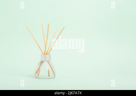 Aromatic Incense, oil diffuser with reed sticks on green background. Closeup, copy space. Stock Photo