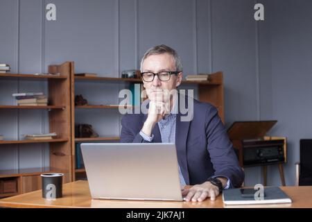 Concentrated senior businessman using laptop in office Stock Photo