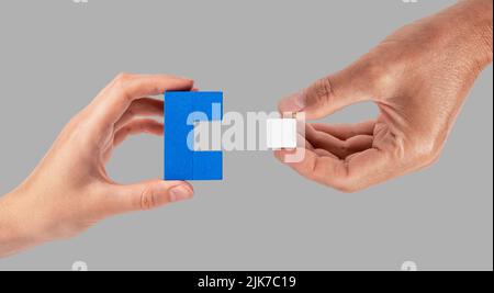 Man and woman hands joining two puzzle pieces. Partnership, connection concept. Partners suitable for each other. High quality photo Stock Photo