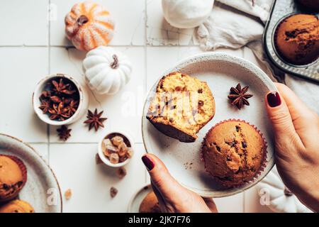 Homemade autumn pumpkin muffins with cinnamon and chocolate on tile background, top view Stock Photo