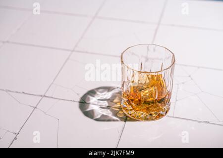Whiskey with ice in glasses, white background with hard light, shadows and sun glare, copy space Stock Photo